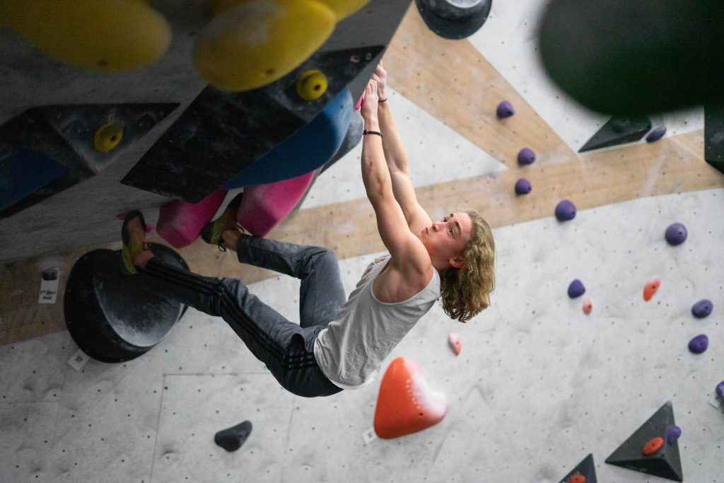 A teen climber hanging from a bouldering wall