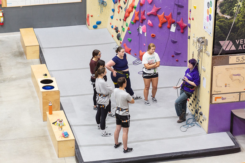 A Vertical Adventures instructor teaching a group of new climbers at the wall