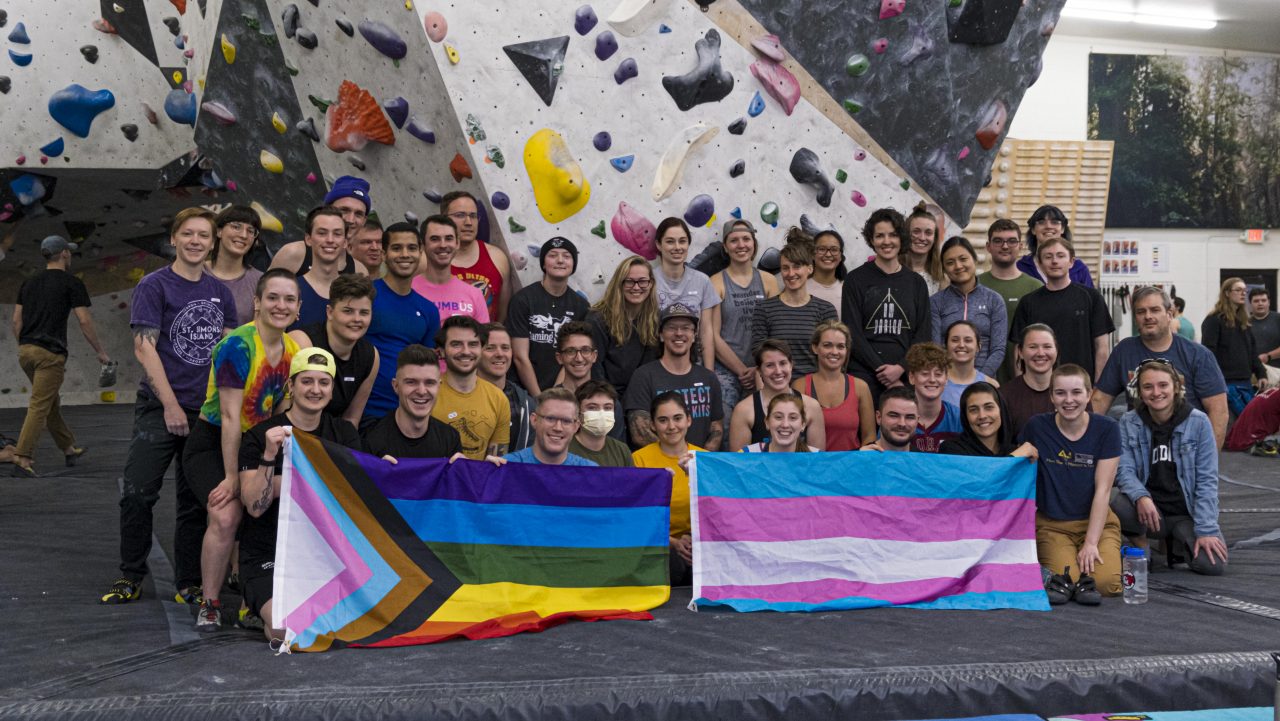 A large group of 5.Life climbers gathered in front of the bouldering wall