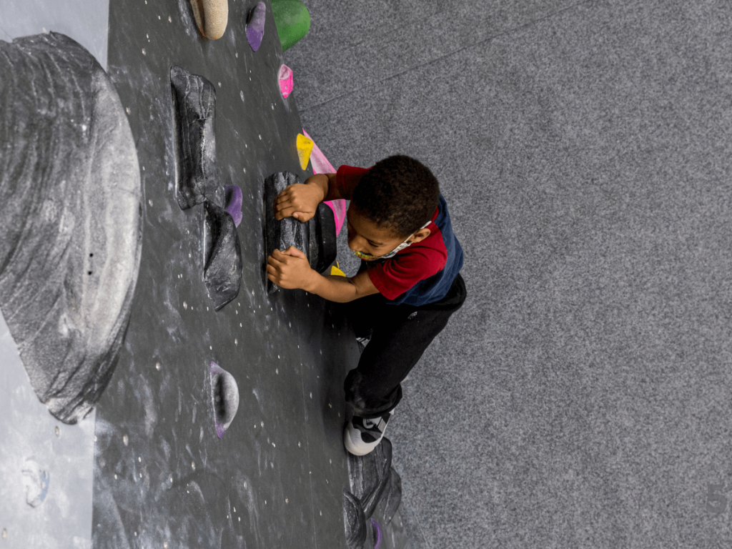 a boy climbing in an indoor climbing gym