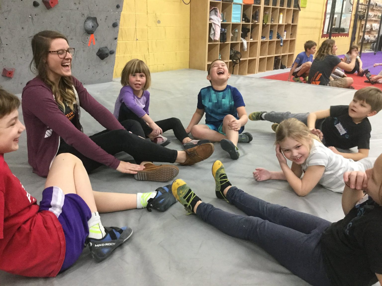 Kids and adults laughing together on the bouldering mats