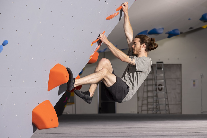 Climber hanging on orange holds on the bouldering wall at Bloc Garten